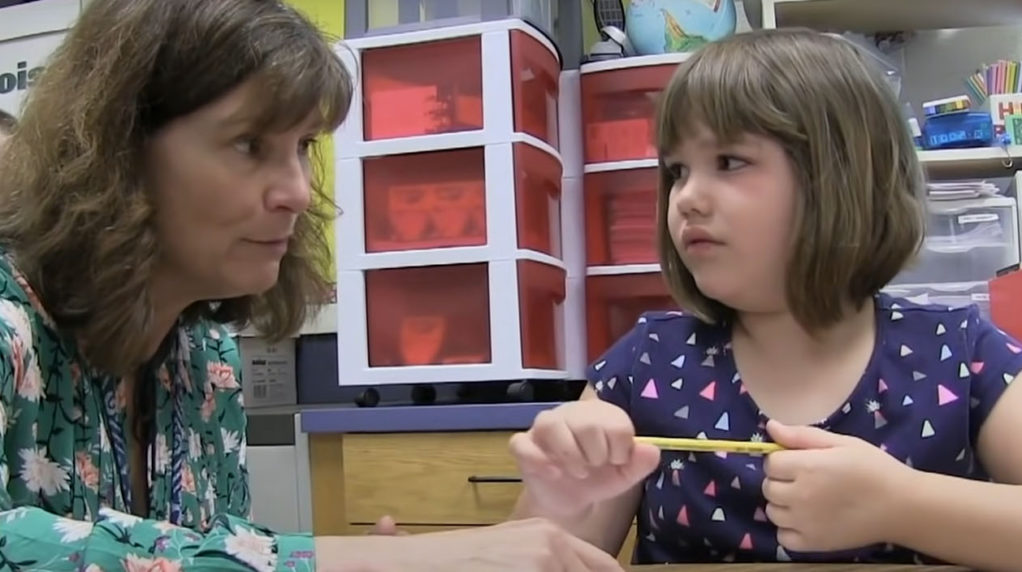 A teacher speaking with a students in a classroom.