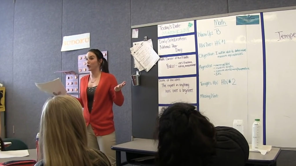 A teacher speaking to students in a classroom.