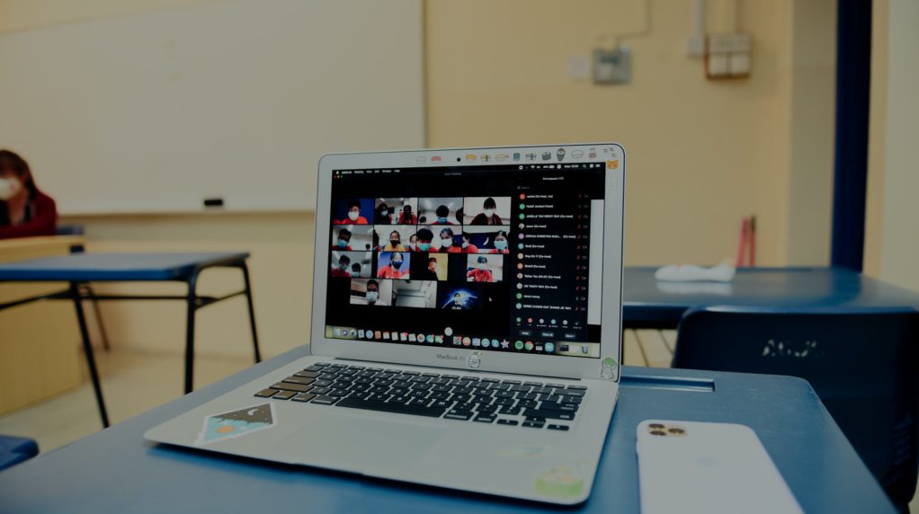 A laptop on a students desk showing a zoom meeting.