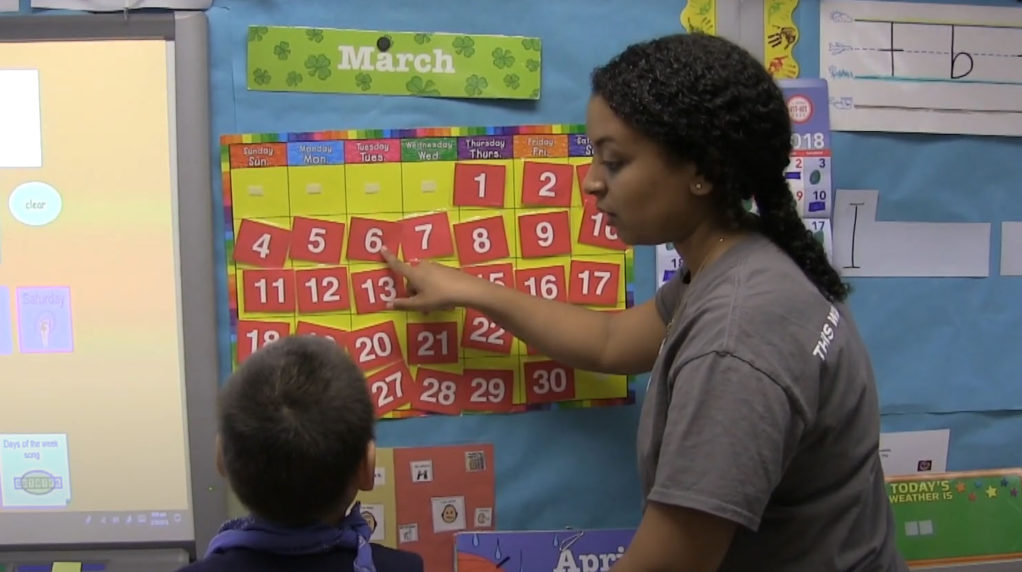 A teacher talking to a student in a classroom.